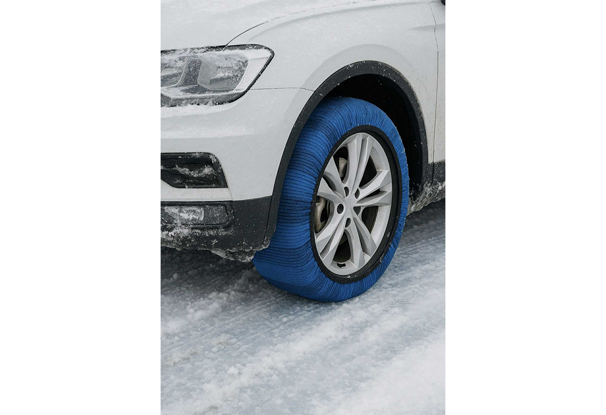 Απεικονίζει ένα αυτοκίνητο με φορεμένες τις χιονοκουβέρτες σε ένα δρόμο με χιόνια